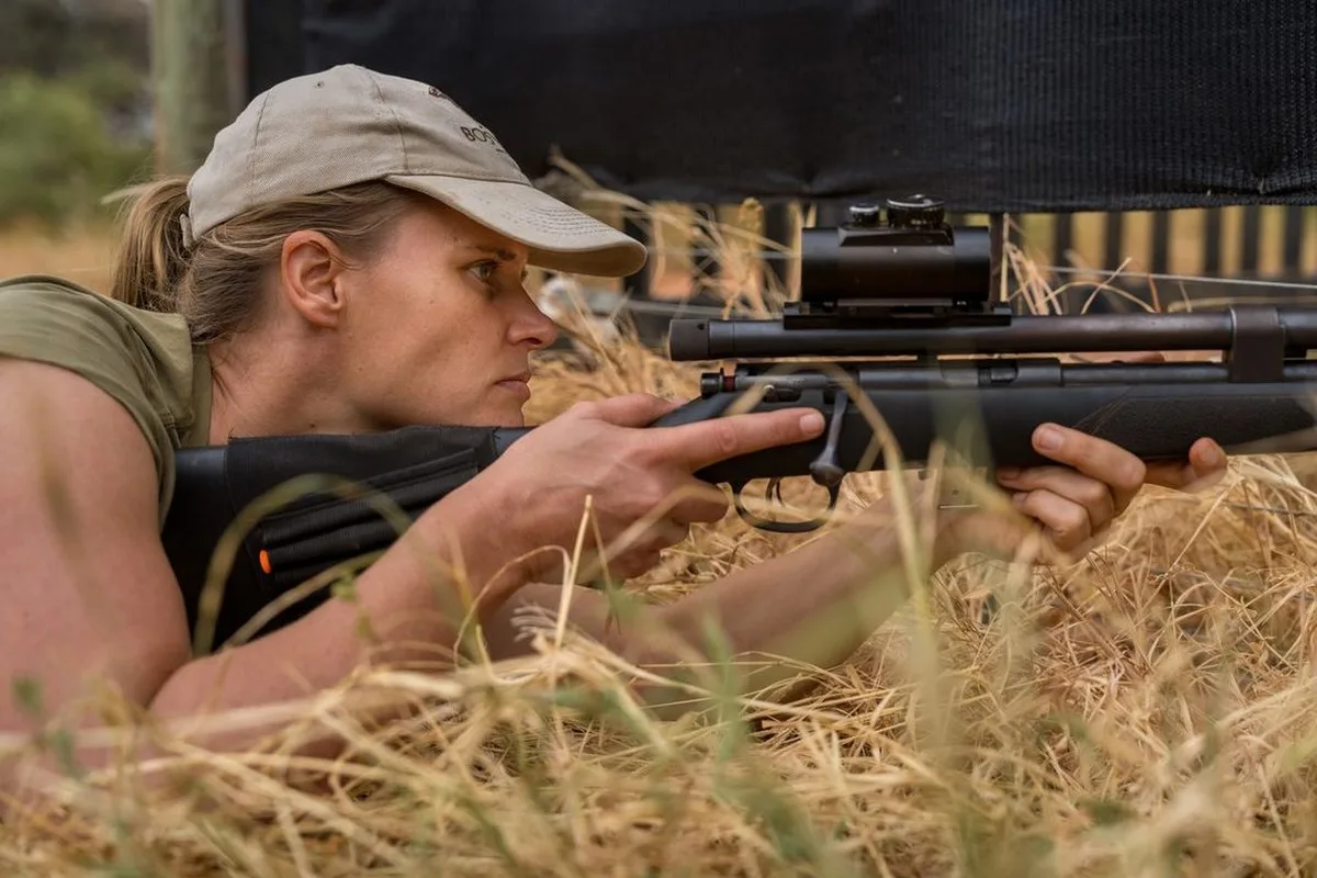 Jana Pauwels, a veterinarian working with the Endangered Wildlife Trust, positions herself to tranquilize an African wild dog in an enclosure.