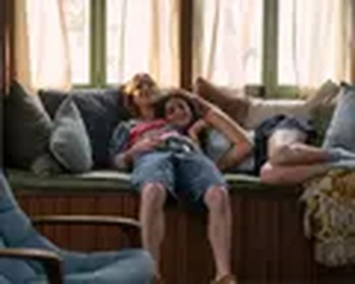 Oona and Annie lie together on a cozy window bench, one resting her head on the other's lap