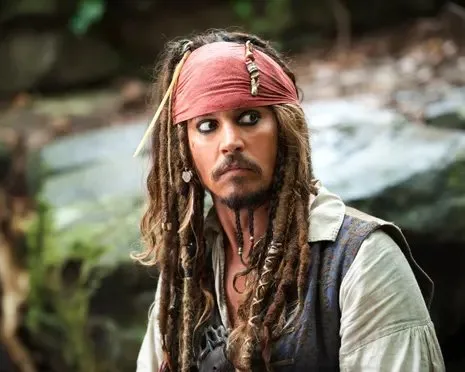 Johnny Depp as Captain Jack Sparrow, in braids and red bandana, looks sideways warily
