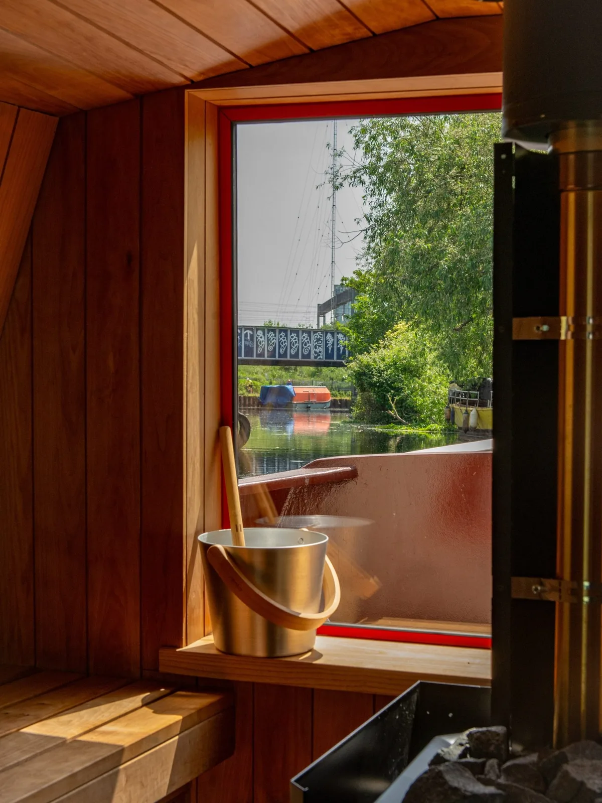Timber-lined sauna with a large picture window overlooking the canal